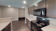Located at 6300 E 45th St in Sioux Falls, South Dakota, this single-floor residence offers a thoughtfully designed layout with modern finishes throughout. The galley-style kitchen is a standout feature, equipped with dark espresso cabinetry, granite-look countertops, black Whirlpool appliances including a range and over-the-range microwave, a double-basin sink, and durable wood-look flooring. A built-in mudroom area adjacent to the kitchen provides a convenient bench and coat hooks for everyday organization. The bedrooms are carpeted and bathed in natural light from sliding windows, offering a comfortable and neutral palette. The bathrooms are well-appointed with granite-look vanity tops, tub-shower combinations, and wood-look flooring. One bathroom opens directly into a spacious walk-in closet, adding practical storage. A dedicated laundry room houses a full-size washer and dryer alongside an overhead storage shelf, enhancing in-unit convenience. The overall aesthetic of the space is clean and contemporary, with neutral tones, recessed lighting, and consistent finishes that create a cohesive and move-in-ready environment throughout.