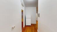 Located at 11 Tetlow St in Boston's Fenway neighborhood, this one-bedroom, one-bathroom unit offers a functional and straightforward layout across a single floor. Warm hardwood flooring runs throughout the main living areas, hallway, and bedroom, lending a cohesive and classic feel to the space. The living room is generously proportioned, featuring multiple windows that allow natural light to fill the room, complemented by a cast-iron radiator that adds a touch of historic character. A dedicated hallway connects the rooms and includes a closet for additional storage. The kitchen is equipped with warm-toned wooden cabinetry, granite-style countertops, and a window that brings in natural light, creating a practical cooking space. The bedroom offers ample room with two windows providing good natural light and ventilation, along with a classic radiator for heating. The bathroom features full tile work on the floors and walls, a soaking bathtub, and a window for ventilation. White walls throughout the unit create a clean, bright atmosphere that complements the natural wood tones of the flooring and cabinetry.