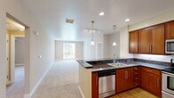 Located at 1201 Race St in San Jose, CA, this single-story residence offers 2 bedrooms and 2 bathrooms across a well-organized, comfortable floor plan. The combined kitchen and living room serves as the heart of the home, featuring rich warm-toned wood cabinetry, dark granite countertops, stainless steel appliances including a range, microwave, and refrigerator, and wood-look flooring. A breakfast bar with pendant lighting connects the kitchen to the carpeted living area, creating an open and functional layout. The spacious primary bedroom is generously sized and receives ample natural light through large sliding windows with views of surrounding greenery. It is accompanied by a full bathroom featuring an extended dual-sink vanity with white cabinetry, a large mirror, and wood-look flooring. The second bedroom is also well-sized with carpeted flooring and a window that brings in natural light. The second bathroom includes a full tub-shower combination, a medicine cabinet, and wood-look flooring. A hallway connects the main living areas to the bedrooms, and a dedicated closet provides additional storage. The warm, neutral color palette throughout creates a cohesive and inviting atmosphere.