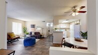 Located at 9225 E Tanque Verde Rd in Tucson, AZ, this 2-bedroom, 1-bathroom single-story residence offers a well-organized and functional layout. The open-concept living, dining, and kitchen area forms the heart of the home, with wood-style flooring flowing throughout the main living spaces. The living room features a fireplace with tile surround, vertical blinds allowing natural light, and a ceiling fan overhead. A breakfast bar connects the living area to the kitchen, which is equipped with white appliances, light wood cabinetry, and a skylight that fills the space with natural light. The dedicated dining area accommodates a round table and benefits from its own window and ceiling fan. The primary bedroom is a comfortable retreat with plush carpeting, a closet, and a window for natural light. The second bedroom features carpet and a hallway connection to the shared full bathroom, which includes a tub-shower combination. A hallway with closet storage adds additional practicality to the floor plan. Textured ceilings are consistent throughout the home, contributing to its classic Southwestern residential character.