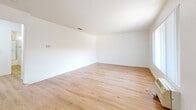 This single-story, 2-bedroom, 1-bathroom unit at 11811 Pioneer Blvd in Norwalk, CA offers a well-organized layout with light wood-style flooring carried consistently throughout every room, creating a cohesive and clean aesthetic. The living room is a comfortable, open space featuring a large window with vertical blinds that allows natural light to fill the room, along with a wall-mounted air conditioning unit for climate control.

The combined kitchen and dining area forms the functional heart of the unit. The galley-style kitchen is equipped with rich, dark wood cabinetry, white countertops, a double stainless steel sink, a gas range, a refrigerator, and a dishwasher. A ceiling fan with a light fixture in the adjoining dining area enhances airflow and visibility. A dedicated pantry provides additional storage.

The spacious primary bedroom is notably generous in size, outfitted with two side-by-side sliding closets with paneled doors. The second bedroom includes its own closet and connects conveniently to the hallway. The single full bathroom features a white vanity with ample cabinet storage, a large mirror, and a tub and shower enclosure with sliding frosted glass doors, complemented by a small window for natural ventilation.