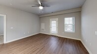 Located at 13100 Margie Ln in Raleigh, NC, this well-appointed 2-bedroom, 2-bathroom home offers a thoughtfully designed single-floor layout. The open-concept kitchen and living area serves as the heart of the home, showcasing light wood-tone cabinetry, white subway tile backsplash, a large center island with an undermount sink, and a full suite of stainless steel appliances including a refrigerator with ice maker, range, microwave, and dishwasher. Stylish pendant lighting illuminates the island, while the adjoining dining and living area benefits from natural light and a ceiling fan. Luxury vinyl plank flooring flows throughout the main living spaces, complemented by warm carpet in both bedrooms. The generously sized primary bedroom features a ceiling fan and windows with exterior views, along with dedicated closet space. The second bedroom, also carpeted and naturally lit, offers convenient access to the main living area. The primary bathroom impresses with a sleek walk-in shower enclosed by frameless sliding glass doors and white subway tile. The second bathroom includes a full tub-shower combination with matching tile. Additional highlights include a private balcony, a pantry, a utility room, an in-unit laundry area, and three closets throughout.