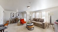 This single-story, 2-bedroom, 1-bathroom residence offers a practical and comfortable layout designed for everyday living. The open living area features soft wall-to-wall carpeting, multiple windows with blinds and curtain panels that invite natural light, and direct access to an exterior door. A dedicated dining area sits adjacent to the living space, creating a seamless flow ideal for entertaining. The kitchen is well-equipped with two-tone cabinetry — white upper cabinets and gray lower cabinets — complemented by white countertops, a classic subway tile backsplash, tile flooring, and stainless steel appliances including a range, microwave, and full-size refrigerator. The primary bedroom is generously sized, featuring plush carpeting, a ceiling fan with light fixture, and ample natural light. Both bedrooms offer a calm, neutral aesthetic well-suited for rest. The shared bathroom includes a full tub-shower combination, tile flooring, a single vanity with white countertop and gray cabinetry, and overhead storage. Two closets provide additional storage, including a walk-in closet with wire shelving. Throughout the home, a clean, neutral color palette and consistent finishes create a cohesive and inviting ambiance.
