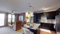 This single-story, two-bedroom, two-bathroom residence offers a thoughtfully designed open-concept layout. The kitchen is a standout feature, equipped with dark espresso cabinetry extending to the ceiling, granite countertops, a mosaic tile backsplash, and a full suite of stainless steel appliances including a refrigerator, range, microwave, and dishwasher. Wood-style flooring grounds the kitchen, which flows seamlessly into a dining area anchored by a granite-topped island with pendant lighting overhead.

The living room connects directly to this space, featuring carpet flooring, a ceiling fan, and large windows that invite natural light. A bold accent wall adds visual interest to the area.

Both bedrooms are carpeted and include ceiling fans and windows with views to the exterior. The primary bedroom benefits from an en-suite bathroom featuring dark cabinetry, granite countertops, and a tub-shower combination with tile surround. The second bathroom mirrors this design with a similar tub-shower configuration. Each bedroom offers access to closet space, completing a functional and cohesive floor plan.