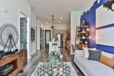 Located on Old Flat Shoals Rd SE in Atlanta, GA, this single-floor residence blends contemporary design with functional living across a well-planned open-concept layout. The kitchen serves as a central hub, outfitted with light wood cabinetry featuring matte black hardware, quartz countertops, subway tile backsplash, and a full suite of stainless steel appliances including a gas range and side-by-side refrigerator. A generously sized island with bar seating connects the kitchen seamlessly to the living area, with pendant lighting overhead enhancing the modern aesthetic.

The living room makes a bold statement with a deep navy accent wall featuring a dramatic skyline-inspired cutout design, creating a striking focal point. Floor-to-ceiling windows flood the space with natural light while offering open urban views, and wood-look flooring runs throughout, adding warmth and cohesion.

The bedroom continues the contemporary theme, with large sliding glass doors framing city views and an accent wall in coordinating navy tones. The bathroom is efficiently designed with a wood-toned vanity, white quartz countertop, glass-enclosed shower, and clean finishes consistent with the rest of the residence. The overall ambiance is modern, urban, and thoughtfully curated.