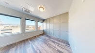 Located in the heart of Manchester, NH, this efficiently designed studio unit offers a thoughtful layout that maximizes every square foot. The combined kitchen and living area serves as the centerpiece of the space, bathed in natural light from large windows that frame views of the surrounding cityscape. The kitchen is outfitted with white shaker cabinetry, open wooden shelving, light quartz countertops, and a full suite of stainless steel appliances, including a refrigerator, electric range, microwave, and dishwasher—all complemented by a matte black faucet and hardware for a modern contrast. Warm-toned luxury vinyl plank flooring runs throughout, tying the open-concept space together seamlessly. A decorative wall paneling detail adds architectural character to the living area, enhancing its visual depth alongside a ceiling-mounted HVAC unit for year-round climate control. The full bathroom features white subway tile surrounding the tub-shower combo, a single vanity with quartz countertop, and matte black fixtures that echo the home's contemporary aesthetic. Additional conveniences include a dedicated laundry area and a closet for storage. Clean lines, neutral tones, and quality finishes define the overall ambiance of this well-appointed urban unit.