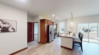 This well-appointed single-floor residence offers a thoughtfully designed layout that balances functionality and modern style. The open-concept kitchen serves as the heart of the home, showcasing rich mahogany-toned cabinetry, stainless steel appliances, and a generously sized center island with a built-in sink, seating, and elegant pendant lighting overhead. Large windows allow natural light to fill the space, creating a bright and inviting atmosphere throughout.

Light-toned hardwood-style flooring flows seamlessly through the main living areas and hallways, complemented by bold dark baseboards that add a striking contrast. The bedrooms are carpeted for comfort, each featuring ceiling fans, ample natural light from large windows, and clean neutral walls that provide a versatile backdrop.

The residence includes two full bathrooms — one with a soaking tub and shower combination, and another with a walk-in shower — both finished with tile flooring and clean white fixtures. A dedicated in-unit laundry room houses a full-size washer and dryer, adding everyday convenience. A spacious entryway with smooth walls and recessed lighting completes this well-rounded, move-in-ready home.