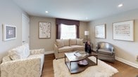 This single-floor residence offers a cohesive and carefully curated interior design throughout its various rooms. The living area serves as a welcoming focal point, featuring rich hardwood flooring, recessed lighting, and a large window dressed with deep plum valances and sheer panels that invite abundant natural light. Comfortable neutral upholstered seating surrounds a sleek glass-top coffee table, creating an elegant yet relaxed atmosphere.

The kitchen is efficiently laid out with dark cabinetry, light countertops, stainless steel appliances including a gas range and over-the-range microwave, and a tile backsplash. Light-toned floor tiles brighten the space, while a window with a colorful roman shade adds a playful accent. A small bistro-style dining setup tucks neatly into the room.

Two bedrooms continue the home's refined aesthetic. The primary bedroom features multiple windows with patterned valances, sheer curtains, a graceful upholstered headboard, coordinating nightstands, and a dark wood dresser. A secondary bedroom showcases a stylish daybed dressed in purple quilted bedding, complemented by decorative ottomans and framed wall art.

The bathroom is finished with classic white tile, contrasting dark accent tile banding, a tub-shower combination with a deep burgundy curtain, and a window with a patterned roman shade, completing this well-appointed home.