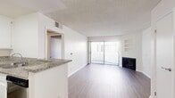 Located at 825 S Hobart Blvd in the heart of Los Angeles, this one-bedroom, one-bathroom unit offers a well-organized and functional layout across a single floor. The open-concept living room and kitchen area serves as the heart of the home, featuring hardwood-style flooring that extends throughout the space. The living room is anchored by a fireplace and a large sliding glass door fitted with vertical blinds, allowing natural light to filter in while providing access to an outdoor area. Built-in wall shelving adds a practical decorative touch alongside the fireplace. The kitchen is efficiently designed with white cabinetry, granite countertops, a stainless steel gas range, dishwasher, and a sink — all offering a clean, modern aesthetic. The bedroom is a comfortable retreat with mirrored sliding closet doors that enhance the sense of space. The bathroom features white cabinetry, a granite-topped vanity, a mirror, and built-in shelving, maintaining the cohesive, clean design found throughout the unit. Textured ceilings are present throughout, and a hallway connects the rooms with ease. The overall ambiance is bright, neutral, and move-in ready.