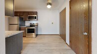 Located at 1540 E Saint Germain St in Saint Cloud, Minnesota, this single-floor unit offers a practical and well-appointed layout designed for comfortable everyday living. The open living area is finished with light wood-style flooring and features a textured ceiling, baseboard heating, and windows that allow natural light to fill the space with views of the surrounding neighborhood greenery.

The kitchen is a functional galley-style design equipped with dark espresso cabinetry, granite-style countertops, stainless steel appliances including a refrigerator, electric range, and over-the-range microwave, as well as a stainless steel sink. Light wood-style flooring continues throughout the kitchen, which also includes a ceiling light fixture and additional closet storage nearby.

The bedrooms are carpeted and include baseboard heating, textured ceilings, and windows providing natural light. One bedroom features a sliding closet door for convenient storage. The full bathroom is accessed through a solid wood door and includes light wood-style tile flooring, dark vanity cabinetry with a granite-style countertop, and a full tub-shower combination with a white surround. The overall aesthetic is clean, neutral, and move-in ready.