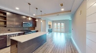 Located in Denver's sought-after Cherry Creek neighborhood, this single-floor residence showcases a thoughtfully designed open-concept layout with contemporary finishes throughout. Wide-plank hardwood flooring flows seamlessly from the gourmet kitchen into the living area, creating a cohesive and inviting atmosphere.

The chef's kitchen is a standout feature, outfitted with rich dark cabinetry extending to the ceiling, a striking mosaic tile backsplash, stainless steel appliances, and a generous island topped with a sleek marble-style quartz countertop. Pendant lighting above the island adds a warm, refined ambiance. The living area includes a fireplace and a stylish barn door accent, opening toward the kitchen and corridor spaces. French doors lead to a private balcony, inviting abundant natural light into the main living space.

The primary bathroom is elegantly appointed with large-format tile flooring, a frameless glass walk-in shower, a dual-sink vanity with quartz countertops, and a dark wood-framed mirror. A spacious walk-in closet with custom shelving and clothing rods provides ample storage. Additional conveniences include a half bathroom, an in-unit laundry area, and clean, light-filled hallways. The overall design balances modern sophistication with functional everyday living.