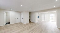 Located in Indianapolis, Indiana, this two-story home offers four bedrooms and three bathrooms across a well-organized floor plan. The main level features an open-concept living room and kitchen area bathed in natural light from large windows with vertical blinds. A standout white-painted brick fireplace anchors the living room, complemented by light hardwood-style flooring and recessed lighting throughout. The kitchen is thoughtfully appointed with white shaker cabinetry, a teal subway tile backsplash, stainless steel appliances including a refrigerator, gas range, microwave, and dishwasher, plus a laundry area nearby. A staircase connects the main level to the upper floor, where four bedrooms are located. The bedrooms feature neutral carpet flooring and windows that bring in natural light. The primary bedroom offers a comfortable, well-proportioned layout. The three bathrooms are cleanly finished, with one featuring a tiled tub-surround with a multi-toned mosaic tile design, matte black fixtures, and grey tile flooring. Additional conveniences include two closets and a hallway connecting the upper-level rooms. The home's clean, neutral palette and updated finishes create a modern, move-in-ready atmosphere throughout.