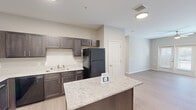 Located on Central Avenue in Chattanooga, Tennessee, this single-story unit offers a thoughtfully designed layout with contemporary finishes throughout. The open-concept kitchen serves as a central hub, showcasing dark espresso cabinetry, granite countertops, a undermount sink, and a spacious island that provides additional prep and seating space. Black appliances, including a full-size refrigerator and over-the-range microwave, complete the kitchen's functional design. Light wood-look flooring flows throughout the main living areas, complementing the neutral gray-toned walls and creating a cohesive, modern aesthetic.

The living area benefits from natural light through sliding glass doors leading to an exterior access point, while bedroom spaces feature windows with blinds and ceiling fans. Each bedroom is paired with a dedicated walk-in closet equipped with wire shelving systems for organized storage.

The unit includes two bathrooms: a full bath with a tub-shower combination and a primary bath featuring a glass-enclosed walk-in shower. Both bathrooms are finished with granite-topped vanities, dark cabinetry, undermount sinks, and light tile flooring. Double doors and well-proportioned rooms throughout contribute to the unit's open, comfortable feel.