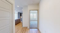 This single-floor, 2-bedroom, 2-bathroom residence offers a clean, contemporary design with a cohesive blend of modern finishes and functional layout. Light hardwood-style flooring flows throughout the main living areas, complementing the bright, neutral palette of white walls and crisp trim. The open-concept kitchen and living area serves as the heart of the home, featuring a well-equipped kitchen with taupe shaker-style cabinetry, granite countertops, a geometric white tile backsplash, stainless steel appliances including a French door refrigerator, and pendant lighting above a spacious island — ideal for both cooking and casual dining. The living area opens to the outdoors through full-length glass doors, bathing the space in natural light and offering pleasant exterior views. The generously sized primary bedroom includes plush carpeting, a ceiling fan, and natural light from a double window, paired with a dedicated closet and an en suite bathroom featuring dual granite vanities, taupe cabinetry, a glass-enclosed walk-in shower, and hardwood-style flooring. The second bedroom also offers carpet, a closet, and ample natural light. The second bathroom includes a soaking tub with marble-tiled surround, granite vanity, and matching finishes. A dedicated laundry room and two closets round out this well-designed residence.
