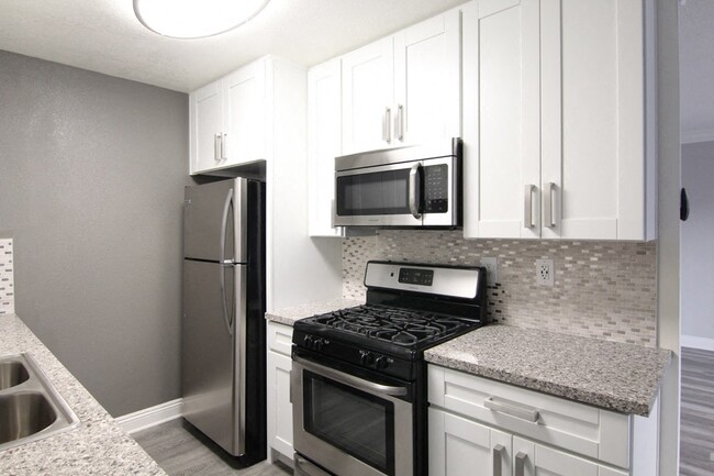 Kitchen with quartz stone counters and stainless steel microwave, oven, fridge, and fixtures. - Cedar Glen