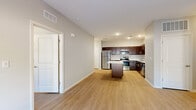 This single-floor residence is designed with a clean, contemporary aesthetic, featuring light hardwood-style flooring and neutral-toned walls that create a bright, cohesive atmosphere throughout. A welcoming entryway corridor leads into the main living areas, offering a seamless flow between spaces.

The kitchen serves as a central highlight, outfitted with rich dark espresso cabinetry, white countertops, and a full suite of stainless steel appliances including a refrigerator, range, microwave, and dishwasher. A freestanding center island provides additional prep and storage space, while recessed lighting illuminates the area effectively.

The open living area adjoins the kitchen and benefits from natural light streaming through a set of glass doors that overlook greenery outside. A ceiling fan adds functional comfort to this generously proportioned room.

The bedrooms are well-sized, each featuring the same hardwood-style flooring, ceiling fans where applicable, and windows fitted with blinds that allow for natural light and privacy. The bathroom includes a walk-in shower enclosed by a glass panel, finished in clean white with brushed nickel hardware. Throughout the unit, white panel doors and consistent trim work reinforce the modern, well-maintained character of the space.