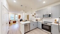 Located at 2005 Empire Street in Charlotte, NC, this well-appointed 2-bedroom, 2-bathroom residence offers a thoughtfully designed single-level layout. The open-concept living, dining, and kitchen area forms the heart of the home, bathed in natural light from large windows and a glass door that leads to a private outdoor area featuring lush turf landscaping and a modern fenced surround.

The kitchen is a standout feature, showcasing sleek gray shaker-style cabinetry, white quartz countertops, a peninsula with an undermount sink, stylish pendant lighting, a subway tile backsplash, and a full suite of stainless steel appliances including a refrigerator, range, microwave, and dishwasher. Light wood-style flooring flows throughout the main living areas, adding warmth and continuity.

The primary bedroom connects to a well-designed en-suite bathroom featuring a glass-enclosed walk-in shower with marble-style tile, a gray double vanity with an illuminated mirror, and direct access to a spacious walk-in closet with built-in shelving. The second bedroom is bright and comfortable, with plush carpet and a generous window. Additional highlights include four closets, an in-unit laundry, and recessed lighting throughout, all combining to create a clean, modern living environment.