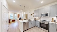 Located at 2005 Empire Street in Charlotte, NC, this well-appointed 2-bedroom, 2-bathroom residence offers a thoughtfully designed single-level layout. The open-concept living, dining, and kitchen area forms the heart of the home, bathed in natural light from large windows and a glass door that leads to a private outdoor area featuring lush turf landscaping and a modern fenced surround.

The kitchen is a standout feature, showcasing sleek gray shaker-style cabinetry, white quartz countertops, a peninsula with an undermount sink, stylish pendant lighting, a subway tile backsplash, and a full suite of stainless steel appliances including a refrigerator, range, microwave, and dishwasher. Light wood-style flooring flows throughout the main living areas, adding warmth and continuity.

The primary bedroom connects to a well-designed en-suite bathroom featuring a glass-enclosed walk-in shower with marble-style tile, a gray double vanity with an illuminated mirror, and direct access to a spacious walk-in closet with built-in shelving. The second bedroom is bright and comfortable, with plush carpet and a generous window. Additional highlights include four closets, an in-unit laundry, and recessed lighting throughout, all combining to create a clean, modern living environment.
