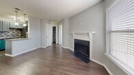 Located at 1919 W Tarrant Rd in Grand Prairie, Texas, this single-story, one-bedroom, one-bathroom unit offers an efficient and well-appointed layout across a modest footprint. Dark hardwood-style flooring runs consistently throughout the space, complementing the neutral gray walls and white trim that give the unit a clean, cohesive aesthetic.

The living room serves as the central gathering area and features a notable wood-burning fireplace with a classic white mantel and dark brick surround, adding both character and functionality. Natural light enters through blinds-fitted windows, and a ceiling fan with integrated lighting enhances comfort in the bedroom. Textured ceilings are present throughout the unit.

The kitchen is thoughtfully updated with gray shaker-style cabinetry, granite countertops, a mosaic tile backsplash, a stainless steel sink, a dishwasher, and a refrigerator — offering a stylish and practical workspace despite its compact galley configuration.

The bedroom provides a comfortable private retreat with access to a dedicated closet featuring built-in shelving and hanging rods. The bathroom includes a full tub-shower combination with white tile surround, a toilet, and overhead cabinetry for storage. The unit's straightforward layout ensures efficient use of every available space.