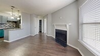 Located at 1919 W Tarrant Rd in Grand Prairie, Texas, this single-story, one-bedroom, one-bathroom unit offers an efficient and well-appointed layout across a modest footprint. Dark hardwood-style flooring runs consistently throughout the space, complementing the neutral gray walls and white trim that give the unit a clean, cohesive aesthetic.

The living room serves as the central gathering area and features a notable wood-burning fireplace with a classic white mantel and dark brick surround, adding both character and functionality. Natural light enters through blinds-fitted windows, and a ceiling fan with integrated lighting enhances comfort in the bedroom. Textured ceilings are present throughout the unit.

The kitchen is thoughtfully updated with gray shaker-style cabinetry, granite countertops, a mosaic tile backsplash, a stainless steel sink, a dishwasher, and a refrigerator — offering a stylish and practical workspace despite its compact galley configuration.

The bedroom provides a comfortable private retreat with access to a dedicated closet featuring built-in shelving and hanging rods. The bathroom includes a full tub-shower combination with white tile surround, a toilet, and overhead cabinetry for storage. The unit's straightforward layout ensures efficient use of every available space.