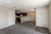 Located at 16950 Jasmine St in Victorville, CA, this single-floor 1-bedroom, 1-bathroom residence offers a functional and well-organized layout. The living area features plush carpeting and warm neutral-toned walls, creating a comfortable and inviting atmosphere. Large sliding glass doors and a secondary window flood the space with abundant natural light while providing views of mature trees and the surrounding outdoor greenery, along with direct access to a private balcony or patio.

The kitchen is designed for efficient use of space, featuring rich dark-toned cabinetry with ample upper and lower storage, light-colored countertops, wood-look flooring, and a full suite of white appliances including a gas range, over-the-range microwave, and sink. A peninsula counter connects the kitchen to the living area, offering additional workspace and a natural division between the two zones.

The bedroom is generously proportioned with soft carpeting, neutral walls, and a closet, with convenient proximity to the bathroom. The bathroom is well-appointed with a wide vanity topped with a white countertop and dark cabinetry, a large wall mirror, and a combined shower and bathtub enclosed with sliding glass doors. Wood-look flooring ties the bathroom together cohesively. Throughout, textured ceilings and consistent warm tones contribute to a cohesive and practical living environment.