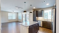 Located at 3600 N A W Grimes Blvd in Round Rock, Texas, this one-bedroom, one-bathroom unit offers a well-designed single-floor layout with modern finishes throughout. The open-concept living and kitchen area forms the heart of the space, where wood-style flooring, large windows, and a sliding glass door to a private balcony fill the area with natural light and outdoor views.

The kitchen is a standout feature, boasting dark espresso cabinetry, a subway tile backsplash, granite countertops, and a central island illuminated by stylish pendant lighting. Stainless steel appliances — including a French door refrigerator, range, microwave, and dishwasher — complete the chef-friendly setup. Track lighting and recessed ceiling fixtures add to the kitchen's functional appeal.

The bedroom is a comfortable retreat, finished with plush carpeting, a ceiling fan, and a window that lets in ample natural light. The bathroom is well-appointed with a dual-sink granite vanity, dark cabinetry with modern hardware, a large mirror, and direct access to a walk-in closet with built-in shelving and hanging rods. The overall ambiance is clean, contemporary, and move-in ready.