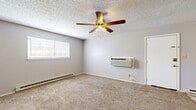 This 2-bedroom, 1-bathroom single-floor unit offers a straightforward and efficient layout designed for comfortable everyday living. The space is organized across a hallway-connected floor plan that includes a living area, galley kitchen, two bedrooms, and a full bathroom.

The living area features wall-to-wall carpet, a ceiling fan with light fixture, a wall-mounted HVAC unit, and baseboard heating — providing year-round climate control. Natural light enters through a window fitted with blinds, keeping the room bright and functional.

The galley-style kitchen is lined with white cabinetry, warm wood-toned countertops, and a matching tile backsplash. White appliances, including a refrigerator, electric range, and dishwasher, are neatly integrated. Diamond-patterned tile flooring completes the kitchen's clean aesthetic.

Both bedrooms are carpeted and include ceiling fans, baseboard heating, and built-in closets with bifold doors. Windows with blinds allow natural light into each room, while neutral gray walls keep the spaces versatile. The primary bedroom also features a wall-mounted HVAC unit.

The bathroom is equipped with a single-sink vanity, a toilet, and a tub-shower combination, all set against neutral tones and diamond-patterned tile flooring. Textured ceilings are present throughout the unit, adding a consistent design element across all rooms.