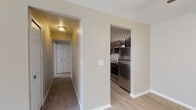 This single-floor residence offers a thoughtfully designed layout that balances functionality and comfort. The entry opens into a living area finished with light hardwood-style flooring that transitions seamlessly into plush carpeting, creating a warm and inviting atmosphere. A ceiling fan overhead adds practical comfort to the space, while vertical blinds along a sliding door allow for abundant natural light and outdoor access.

The galley-style kitchen is well-equipped, featuring rich dark cabinetry with ample upper and lower storage, light stone-toned countertops, and a full suite of stainless steel appliances including a refrigerator, range, and built-in microwave. The light hardwood-style flooring continues throughout this space, complementing the overall design aesthetic.

A carpeted hallway connects the main living areas to the bedrooms, each of which is finished with soft wall-to-wall carpeting and neutral-toned walls. The bedrooms benefit from natural light through windows dressed with vertical blinds, and one room includes a closet with traditional paneled doors.

The bathroom is clean and functional, offering a full-sized soaking tub with shower, a toilet, and a vanity with dark cabinetry and a light countertop surface. Consistent neutral tones and white trim are carried throughout the entire residence, lending the space a cohesive and move-in-ready appeal.