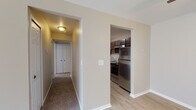 This single-floor residence offers a thoughtfully designed layout that balances functionality and comfort. The entry opens into a living area finished with light hardwood-style flooring that transitions seamlessly into plush carpeting, creating a warm and inviting atmosphere. A ceiling fan overhead adds practical comfort to the space, while vertical blinds along a sliding door allow for abundant natural light and outdoor access.

The galley-style kitchen is well-equipped, featuring rich dark cabinetry with ample upper and lower storage, light stone-toned countertops, and a full suite of stainless steel appliances including a refrigerator, range, and built-in microwave. The light hardwood-style flooring continues throughout this space, complementing the overall design aesthetic.

A carpeted hallway connects the main living areas to the bedrooms, each of which is finished with soft wall-to-wall carpeting and neutral-toned walls. The bedrooms benefit from natural light through windows dressed with vertical blinds, and one room includes a closet with traditional paneled doors.

The bathroom is clean and functional, offering a full-sized soaking tub with shower, a toilet, and a vanity with dark cabinetry and a light countertop surface. Consistent neutral tones and white trim are carried throughout the entire residence, lending the space a cohesive and move-in-ready appeal.