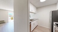 Located at 5353 Baltimore Dr in La Mesa, CA, this efficiently designed single-floor unit offers a thoughtfully arranged layout that maximizes every square foot. Light wood-style flooring runs throughout the space, complementing the neutral, warm-toned walls and textured ceilings for a clean, contemporary feel.

The kitchen is a standout feature, outfitted with white shaker-style cabinetry — both upper and lower — paired with sleek gray countertops. Stainless steel appliances include a refrigerator, range, over-the-range microwave, and dishwasher, while a subway tile backsplash adds a modern touch. The kitchen opens via a peninsula counter directly into the living area, creating a seamless, open-concept flow.

The living room is bright and airy, bathed in natural light through a large sliding glass door that provides direct access to an outdoor patio area with views of lush landscaping and a pool. An additional window further enhances the light-filled ambiance of the space.

The bathroom features a tub-shower combination, toilet, and wood-style flooring consistent with the rest of the unit. A dedicated closet provides convenient storage. The overall design is cohesive and modern, ideal for comfortable everyday living in the sunny Southern California climate.