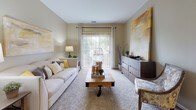 Located at 303 Mill Pond Ln in Salisbury, Maryland, this well-appointed single-floor residence offers a thoughtfully designed layout with a warm, neutral color palette throughout. The living room is a welcoming centerpiece, featuring plush carpeting, large sliding glass doors that flood the space with natural light and provide outdoor views, and ample room for comfortable furnishings. Adjacent to the living area, the kitchen is equipped with light wood cabinetry, dark granite-style countertops, hardwood flooring, and white appliances including a range and full-size refrigerator. A breakfast bar with industrial-style stools connects the kitchen to the main living space, offering a casual dining option. A separate dining area accommodates a full table and chairs, providing a dedicated space for meals. The residence includes multiple bedrooms, each carpeted and featuring windows with views of the surrounding area. The primary bedroom includes a ceiling fan, generous floor space, and access to a private area. Two full bathrooms feature light wood vanities, white countertops, hardwood flooring, and tub-shower combinations with tile surrounds. Closet storage is available throughout, and the overall ambiance is bright, comfortable, and cohesive.
