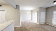 This thoughtfully laid-out 2-bedroom, 1-bathroom unit in Austin, TX offers a comfortable and efficient use of space across a single floor. The open living area is finished with plush carpet and neutral-toned walls, creating a warm and inviting atmosphere. A pendant light fixture anchors the space, while a sliding glass door fitted with vertical blinds allows natural light to fill the room. The kitchen features a galley-style layout with white cabinetry, light countertops, wood-look flooring, and black appliances including a range and dishwasher. A set of double bi-fold doors provides convenient pantry or storage access. Both bedrooms are carpeted and feature ceiling fans with light kits and windows dressed with blinds that let in natural light. The spacious primary bedroom includes a walk-in closet with built-in shelving, offering generous storage. The second bedroom is equally well-appointed with its own closet space. The bathroom includes a full tub-shower combination with white tile surround, safety grab bars, wood-look flooring, and overhead cabinetry for additional storage. A hallway connects the rooms seamlessly, completing this clean and functional floor plan.