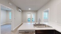 Located at 1866 Lincoln Ave in the heart of Calistoga, CA, this thoughtfully designed 2-bedroom, 2-bathroom residence offers a clean, modern aesthetic throughout its single-floor layout. Light-toned luxury vinyl plank flooring flows seamlessly across the living spaces, complementing the neutral wall palette and crisp white trim.

The open-concept kitchen, dining, and living area serves as the heart of the home. The kitchen is outfitted with rich dark-espresso cabinetry, white quartz countertops, stainless steel appliances including a refrigerator, range, microwave, and dishwasher, and a peninsula with an undermount sink. Recessed lighting illuminates the space, which opens directly to the living area and a glazed door leading to a private balcony.

Both bedrooms feature large windows with vertical blinds that frame lush green outdoor views, filling each room with natural light. Each bedroom includes a sliding-door closet with built-in hanging rods, providing practical storage.

The two bathrooms are finished with dark-stained vanity cabinetry, white countertops, large mirrors with overhead lighting, and neutral tile flooring. One bathroom features an open walk-in shower, while the other includes a shower/tub combination. A wall-mounted mini-split system provides efficient climate control throughout the residence.