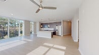 Located at 1110 Metropolitan Ave in Summerville, SC, this well-appointed single-story home offers three bedrooms and three full bathrooms across a thoughtfully designed floor plan. Light hardwood-style flooring flows throughout, complementing a neutral color palette that creates a bright, cohesive atmosphere.

The open-concept kitchen and living area serves as the heart of the home. The kitchen features dark espresso cabinetry, a granite-topped island with pendant lighting, stainless steel appliances including a French door refrigerator and microwave, and a clean white tile backsplash. A ceiling fan and expansive floor-to-ceiling windows flood the living area with natural light and offer picturesque wooded views.

The bedrooms are generously proportioned, each featuring ceiling fans and large windows that invite ample sunlight. The primary bedroom is notably spacious, with access to a well-equipped en-suite bathroom showcasing a dark wood vanity with granite countertops, a large frameless glass walk-in shower with white tile surround, and modern fixtures. A dedicated closet with built-in wire shelving provides excellent storage.

The home also includes a practical laundry room with a full-size Whirlpool washer and dryer, plus additional wire shelving. Clean hallways with recessed lighting connect all areas seamlessly, reinforcing the home's modern and functional design.