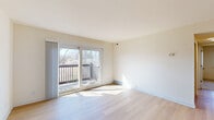 This well-appointed 2-bedroom, 1-bathroom single-floor residence offers a functional and comfortable layout designed for everyday living. The combined kitchen and living room serves as the heart of the home, featuring light hardwood-style flooring, a ceiling fan with integrated lighting, and a sliding glass door that opens onto a private balcony with outdoor views — flooding the space with natural light. The kitchen is equipped with warm-toned wooden cabinetry, granite-style countertops, a stainless steel sink, and black appliances including a range and built-in microwave.

Both bedrooms are carpeted and offer a quiet, comfortable retreat, each with ceiling fans and ample natural light from windows with blinds. The primary bedroom is a generously sized room, and the second bedroom provides solid additional space. Two closets contribute practical storage throughout the unit.

The full bathroom features earthy slate-style tile flooring, a wood-tone vanity, and a full shower-tub combination with built-in shelving. A connecting hallway ties all rooms together cohesively. Throughout, the space maintains a clean, neutral palette of whites and warm creams, creating a bright and welcoming ambiance suitable for a variety of lifestyles.