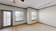 This single-story, 2-bedroom, 2-bathroom home in Humble, TX offers a thoughtfully designed layout with quality finishes throughout. The kitchen serves as a central highlight, showcasing rich dark cabinetry, granite countertops, a subway tile backsplash, and a suite of stainless steel appliances including a range, microwave, and refrigerator. A peninsula with pendant lighting and an integrated sink connects the kitchen seamlessly to the living area.

The living room features plush carpet, crown molding, a ceiling fan, built-in shelving with an arched niche, and a window that invites natural light. Both bedrooms are carpeted and equipped with ceiling fans; the primary bedroom includes a dedicated walk-in closet with wire shelving, offering generous storage.

The bathrooms are finished with dark wood cabinetry, granite countertops, and tiled tub-shower combinations accented with a classic checkered tile border. The primary bath includes a dual-sink vanity with a large mirror. Hardwood-style flooring flows through the bathrooms, adding warmth and continuity.

A dedicated laundry room with wire shelving accommodates a full-size washer. The overall aesthetic balances neutral tones, dark wood accents, and modern fixtures to create a functional and cohesive living environment.