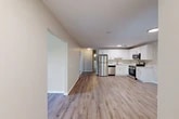 Located at 77 Clinton St in New York Mills, NY, this single-floor, three-bedroom, two-bathroom unit offers a well-organized layout designed for comfortable everyday living. Light-toned luxury vinyl plank flooring runs consistently throughout, lending a clean, cohesive look to every room.

The open-concept kitchen and dining area is a standout feature, equipped with crisp white shaker cabinetry, light marble-style countertops, and a full suite of stainless steel appliances including a refrigerator, dishwasher, range, and over-the-range microwave. The adjoining living area provides generous space and flows naturally into the rest of the home via a central hallway.

The three bedrooms are finished in neutral tones with large windows that invite natural light and offer views of the surrounding tree-lined landscape. The primary bedroom is a comfortable, well-proportioned retreat. Two closets provide additional storage throughout the unit.

The two bathrooms are cleanly appointed with white tile and white vanities. A dedicated laundry room houses a full-size washer and dryer, adding everyday convenience. A utility room rounds out the functional spaces. Baseboard heating is present throughout, ensuring year-round comfort in this efficiently designed home.