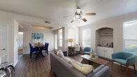 This single-floor residence offers a thoughtfully designed layout that balances comfort and functionality. The open-concept living and dining area serves as the heart of the home, featuring rich hardwood-style flooring, crown molding, and a ceiling fan with integrated lighting. Multiple windows dressed with blinds flood the space with natural light, while a distinctive arched built-in niche with cabinetry and shelving adds architectural character. The living area flows seamlessly into a dedicated dining space, making it well-suited for both everyday living and entertaining.

The galley-style kitchen is outfitted with white shaker cabinetry, granite-look countertops, and a full suite of stainless steel appliances including a refrigerator, electric range, and over-the-range microwave. Dark hardwood-style flooring continues throughout, and an in-unit laundry area is conveniently accessible directly from the kitchen.

The bedroom is a serene retreat, carpeted for comfort and illuminated by a ceiling fan and natural light from multiple windows. A spacious walk-in closet provides generous storage. The room's neutral tones and clean lines contribute to a calm, restful atmosphere.

Overall, the space presents a cohesive aesthetic with neutral walls, consistent finishes, and practical design details that make it both livable and inviting.
