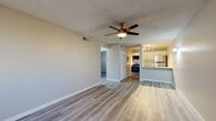 This single-floor residence offers a clean, modern aesthetic with consistent wood-look luxury vinyl plank flooring flowing throughout every room. The open living area is bright and spacious, anchored by a ceiling fan with integrated lighting and a textured ceiling, creating a comfortable and functional gathering space that connects seamlessly to the kitchen and adjacent bedroom areas.

The kitchen is thoughtfully designed with crisp white upper cabinetry, gray lower cabinets fitted with brushed nickel hardware, and white quartz countertops. A classic white subway tile backsplash adds visual interest, while stainless steel appliances — including a refrigerator, range, and microwave — provide a polished, contemporary finish. A breakfast bar creates an easy transition between the kitchen and living area.

The bedrooms are generously sized with neutral warm-toned walls, textured ceilings, and windows that allow natural light to brighten each room, creating an airy and restful atmosphere.

The bathroom features a clean, updated design with gray cabinetry, white quartz countertops, a single-basin sink, and a full tub-shower combination. Consistent flooring and bright white fixtures tie the space together with a cohesive, modern sensibility throughout.