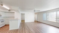 Located at 7009 Interbay Blvd in Tampa, Florida, this single-floor, three-bedroom, two-bathroom home offers a practical and well-organized layout with a bright, neutral aesthetic throughout. The open-concept kitchen and living area forms the heart of the home, featuring white cabinetry, a peninsula breakfast bar with a built-in sink, white appliances, and warm wood-look flooring that extends into the living space. A ceiling fan overhead and a large window allow natural light to fill the living room, creating an airy atmosphere. The three bedrooms are carpeted for comfort, each with ceiling fans and ample natural light from generously sized windows fitted with vertical blinds. The primary bedroom includes its own walk-in closet with wire shelving systems, while additional closets throughout the home provide extensive storage. The two bathrooms are clean and functional, finished with wood-look flooring, white tub-shower combos, and vanities with light countertops. A dedicated laundry room houses a full-size washer and dryer with additional wire shelving and a window for ventilation. The home's consistent use of light tones and practical finishes creates a cohesive, move-in-ready environment.