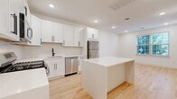 Located at 325-327 Union Blvd in Totowa, NJ, this well-appointed 2-bedroom, 2-bathroom unit offers a thoughtfully designed single-floor layout. The open-concept kitchen and dining area serves as the heart of the home, featuring crisp white shaker cabinets with matte black hardware, quartz countertops, a central island, and a full suite of stainless steel appliances including a gas range, microwave, dishwasher, and refrigerator. Light-toned hardwood flooring runs throughout, lending warmth and continuity across every room. The living area provides generous space with a clean, bright aesthetic enhanced by recessed lighting and neutral white walls. The spacious primary bedroom accommodates a comfortable retreat, while the second bedroom offers natural light through double windows with street views. Both bathrooms are finished in a modern style; one features large-format grey floor tiles, a frameless sliding glass shower enclosure, a white vanity, and matte black fixtures. Additional conveniences include three closets for ample storage, a dedicated laundry area, and a central hallway connecting all rooms seamlessly. The overall design is clean, contemporary, and move-in ready.