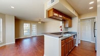 This single-floor residence offers a thoughtfully designed layout that blends comfort and functionality throughout. The open-concept living area is a standout feature, showcasing rich hardwood flooring, a ceiling fan with light fixture, and a generously sized bay window arrangement that floods the space with natural light. A pass-through peninsula connects the living area to the kitchen, creating a seamless flow ideal for everyday living and entertaining.

The galley-style kitchen is well-equipped with warm oak cabinetry, dark granite-look laminate countertops, a double stainless steel sink, black appliances including a refrigerator and cooktop, and a dishwasher. Upper cabinets with a pass-through window opening toward the living space enhance the open feel of the kitchen.

The bedrooms are carpeted for comfort, each featuring ceiling fans with lighting and multiple windows fitted with blinds that invite natural light while maintaining privacy. The neutral wall tones throughout the home create a calm, cohesive aesthetic.

Both bathrooms are finished with classic white subway tile surrounds accented by a decorative diamond-pattern tile border in the tub-shower combinations. Each bathroom includes warm wood-toned cabinetry, granite-look countertops, and well-lit vanity mirrors, offering a clean and timeless design.