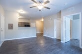 Located at 414 Jefferson Street Ext in Newnan, GA, this single-floor unit offers a well-designed, open-concept layout that maximizes functionality and comfort throughout. Durable hardwood-style flooring flows consistently across the main living areas, lending a cohesive and clean aesthetic to the space.

The living area is generously sized and brightened by natural light, with a ceiling fan overhead and French doors that open to an outdoor area, providing a seamless indoor-outdoor connection. A half-wall pass-through connects the living space to the kitchen, enhancing the open feel while maintaining a sense of definition between the areas.

The galley-style kitchen is efficiently organized with dark cabinetry, light granite-style countertops, and a full suite of black appliances including a refrigerator, electric range, microwave, and dishwasher. The layout makes excellent use of available space with ample storage on both sides.

The bedroom is a comfortable retreat, complete with a ceiling fan and direct access to a private en-suite bathroom. The bathroom features light tile flooring, a vanity with dark wood cabinetry, and a tub-shower combination. Additional rooms and closet space round out the practical, thoughtfully arranged floor plan, making this a functional and inviting living space.