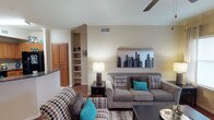 This single-floor residence offers a thoughtfully designed layout that balances comfort and functionality. The living area serves as the heart of the home, featuring warm neutral-toned walls, crown molding, hardwood-style flooring, and a ceiling fan overhead. Built-in shelving adds architectural interest, while natural light filters in through blinded windows to create an inviting atmosphere.

The kitchen is well-equipped for everyday living, showcasing rich honey-toned cabinetry, dark granite countertops, a double-basin stainless steel sink, and a full suite of black appliances including a range, microwave, dishwasher, and refrigerator. Pendant lighting and a breakfast bar with counter seating connect the kitchen to the main living space.

The primary bedroom is generously sized, featuring plush carpeting, a ceiling fan with light fixture, and large windows dressed with grommet-panel curtains. The en-suite bathroom offers a lengthy double-vanity with granite countertops, ample cabinet storage, and a tub-shower combination with tile surround. A second bedroom mirrors the comfort of the primary, with soft carpet, natural light, and ceiling fan. Its adjoining bathroom features a granite-topped vanity, large mirror, and a tiled tub-shower combo. Throughout, the warm, neutral palette and consistent finishes create a cohesive and welcoming environment.