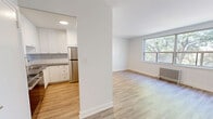 Located at 4979 Bathurst Street in Toronto's North York neighbourhood, this well-appointed one-bedroom, one-bathroom unit offers a thoughtfully updated interior with a clean, modern aesthetic. Light-toned hardwood flooring runs throughout, creating a warm and cohesive feel across every room.

The open living area is generously proportioned, filled with natural light from a large picture window that frames views of mature trees lining the street. A classic cast-iron radiator provides efficient heating, adding a subtle architectural character to the space. The kitchen features crisp white shaker-style cabinetry, grey laminate countertops, a subway tile backsplash, stainless steel appliances including a full-size refrigerator, and an undermount sink — combining practicality with a contemporary finish.

The spacious primary bedroom is comfortably sized, offering two windows with treetop views, a cast-iron radiator, and the same warm hardwood flooring, creating a bright and tranquil retreat. The bathroom is finished with floor-to-ceiling white subway tile surrounding a full soaker tub and shower, polished chrome fixtures, and a clean, minimal design. A connecting hallway ties the layout together efficiently. The overall ambiance is bright, fresh, and move-in ready.