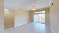 This single-floor residence offers a thoughtfully designed layout with a cohesive, neutral color palette and quality finishes throughout. The open-concept kitchen is a standout feature, equipped with rich dark-wood cabinetry, granite countertops, stainless steel appliances including a refrigerator and range, and a peninsula with pendant lighting above — seamlessly connecting to the main living and dining areas. The living area is bright and airy, benefiting from a large sliding glass door with transom windows above that invite natural light and provide outdoor views. Crown molding and tile flooring lend a polished look to the common areas. The bedrooms are carpeted and comfortable, with ceiling fans, crown molding, and windows offering views of the surrounding area. The bathrooms are well-appointed, featuring granite vanity countertops with dark-wood cabinetry, framed mirrors, and a tiled walk-in shower. Additional utility spaces and interior doors with arched paneling add to the home's practical appeal. The overall ambiance is clean, bright, and move-in ready, offering a welcoming environment with consistent design elements carried throughout the entire floor plan.