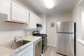 Located at 14801 Bowie Rd in Laurel, MD, this well-appointed 2-bedroom, 1-bathroom residence offers a thoughtfully designed single-floor layout. The combined living and dining area is a standout feature, bathed in natural light through a large sliding glass door that opens onto a private balcony overlooking lush, mature trees — creating a serene, nature-connected atmosphere. The living space is finished with light hardwood-style flooring that extends throughout the main areas, lending a clean and modern feel.

The kitchen is efficiently arranged with crisp white shaker-style cabinetry, granite-look countertops, a stainless steel sink, and a full suite of stainless steel appliances including a gas range, dishwasher, and refrigerator. Tile wainscoting adds a practical and polished touch along the kitchen walls.

Both bedrooms feature plush wall-to-wall carpeting in neutral tones. The primary bedroom is generously sized with dual windows that invite ample natural light and offer pleasant outdoor views. The second bedroom also features carpeting and direct hallway access. Three closets throughout the unit provide excellent storage. The bathroom is finished with tile surround, a white vanity with under-cabinet storage, and a mirror with overhead lighting. A hallway connects all rooms cohesively throughout this comfortable and functional residence.