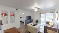 This single-floor residence offers a comfortable and functional layout across several well-defined living spaces. The living room serves as the heart of the home, featuring wood-look flooring, a ceiling fan, and large sliding glass doors fitted with vertical blinds that allow abundant natural light to filter in. The space is open enough to accommodate a full seating arrangement and flows seamlessly toward the dining area.

The kitchen is equipped with dark cabinetry, white countertops, a single-basin sink, a black electric range, a built-in dishwasher, and overhead exhaust ventilation — providing a practical setup for everyday cooking. A skylight-style overhead fixture adds brightness to the workspace.

The primary bedroom is a well-sized retreat featuring wood-look flooring, a ceiling fan, and a window with vertical blinds. The second bedroom offers a similarly comfortable layout with its own ceiling fan and closet. Both bathrooms include tub-shower combinations and wood-look tile flooring, maintaining a consistent aesthetic throughout.

A dedicated in-unit laundry area houses a full-size washer and dryer, adding a convenient amenity. The overall design is clean and neutral, with white walls and consistent flooring creating a cohesive feel across all rooms.