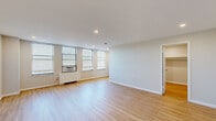 Located at 979 Asylum Ave in Hartford, Connecticut, this single-floor unit offers a clean, modern aesthetic throughout. The main living area is generously proportioned, featuring light-toned hardwood flooring and crisp white walls that create a bright, airy atmosphere. A row of multiple windows fitted with horizontal blinds floods the space with natural light, while recessed ceiling lighting provides additional illumination. A wall-unit air conditioner and radiator ensure year-round climate comfort.

The kitchen is thoughtfully designed with white shaker-style cabinetry, light quartz countertops, and a classic white subway tile backsplash. Stainless steel appliances, including a gas range and an over-the-range microwave, lend a contemporary, functional character to the space.

The layout, as seen in the dollhouse view, reveals a well-organized floor plan that includes a spacious open living area, a dedicated walk-in closet with built-in shelving, and a bathroom. The bathroom is finished with neutral tile flooring and clean white walls, maintaining the consistent, understated palette found throughout the unit.

Overall, this space presents a move-in-ready environment with a cohesive modern finish, practical storage solutions, and an abundance of natural light — well-suited for comfortable everyday living in Hartford's Asylum Hill neighborhood.