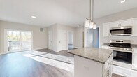 Located at 1055 Bridgeport Avenue in Shelton, CT, this thoughtfully designed 2-bedroom, 1-bathroom residence offers a clean, modern aesthetic throughout its well-appointed single floor. The open-concept kitchen and living area serves as the heart of the home, featuring white shaker cabinetry, granite countertops, stainless steel appliances, and a central island with elegant pendant lighting overhead. Wood-style flooring flows seamlessly throughout, complementing the neutral-toned walls and crisp white trim. The living area is bathed in natural light and opens to a private balcony through sliding glass doors, providing outdoor views of the surrounding landscape. The spacious primary bedroom features multiple windows that flood the room with sunlight and offer pleasant outdoor views, along with a dedicated closet. The second bedroom is equally bright and well-sized with its own window and closet access. The full bathroom is finished with a granite-topped vanity, white cabinetry, and a tub-shower combination. Three closets provide generous storage throughout the residence. A dedicated laundry area adds everyday convenience. The overall ambiance is bright, clean, and move-in ready, reflecting a contemporary residential design ideal for comfortable living.